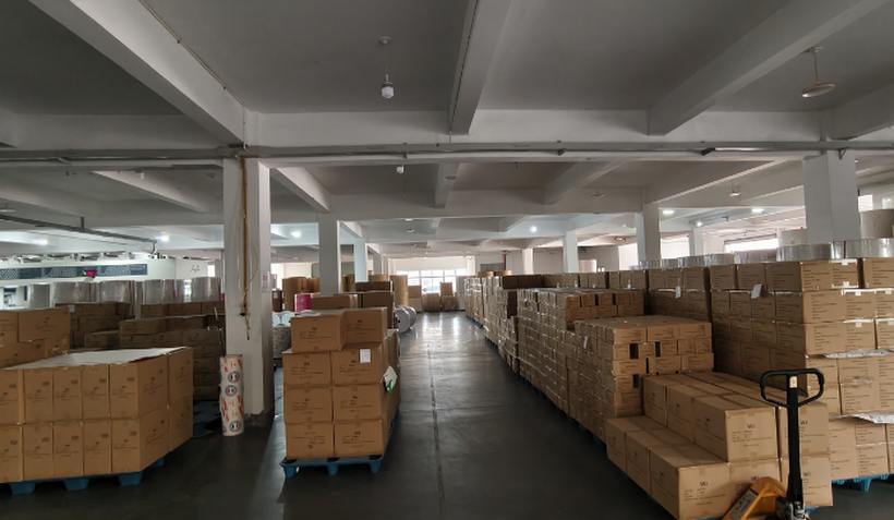 Warehouse aisle with palletized napkin cartons stacked and labeled